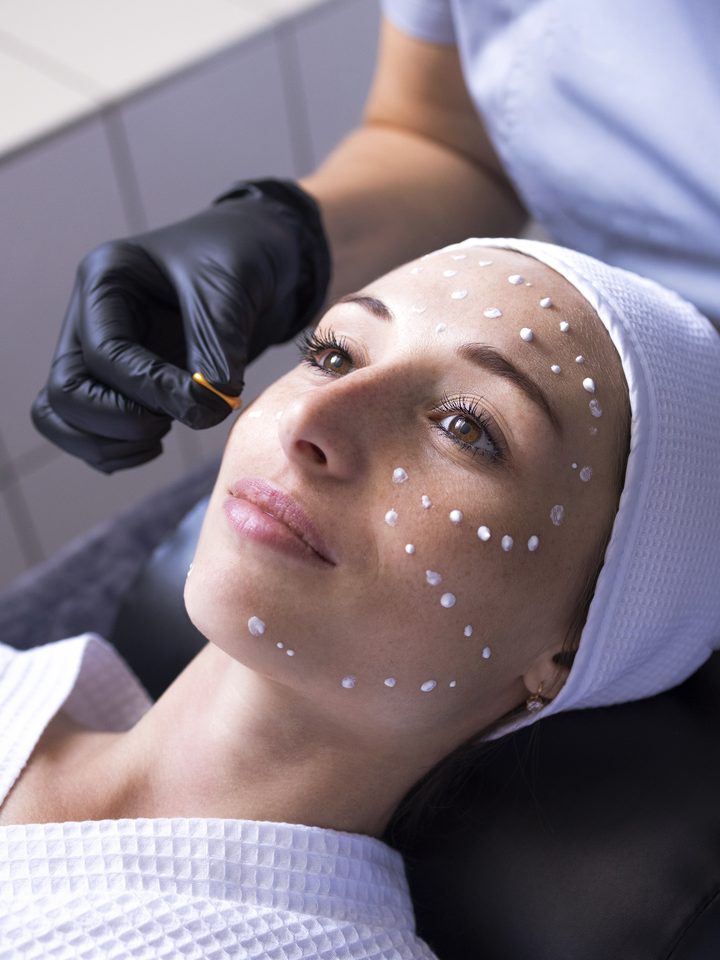 A therapist applying treatment product to a client's face during a facial.