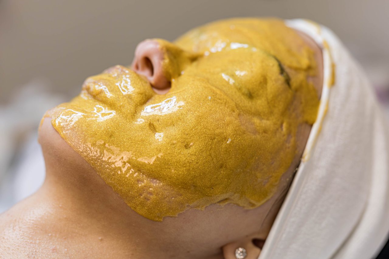 A gold treatment mask covering the face, held back by a headband.