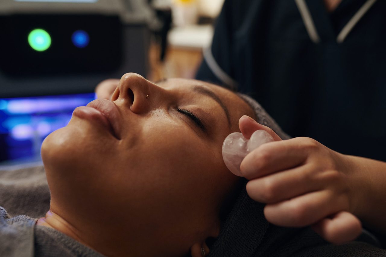 A facial massage being given with a smooth stone tool.