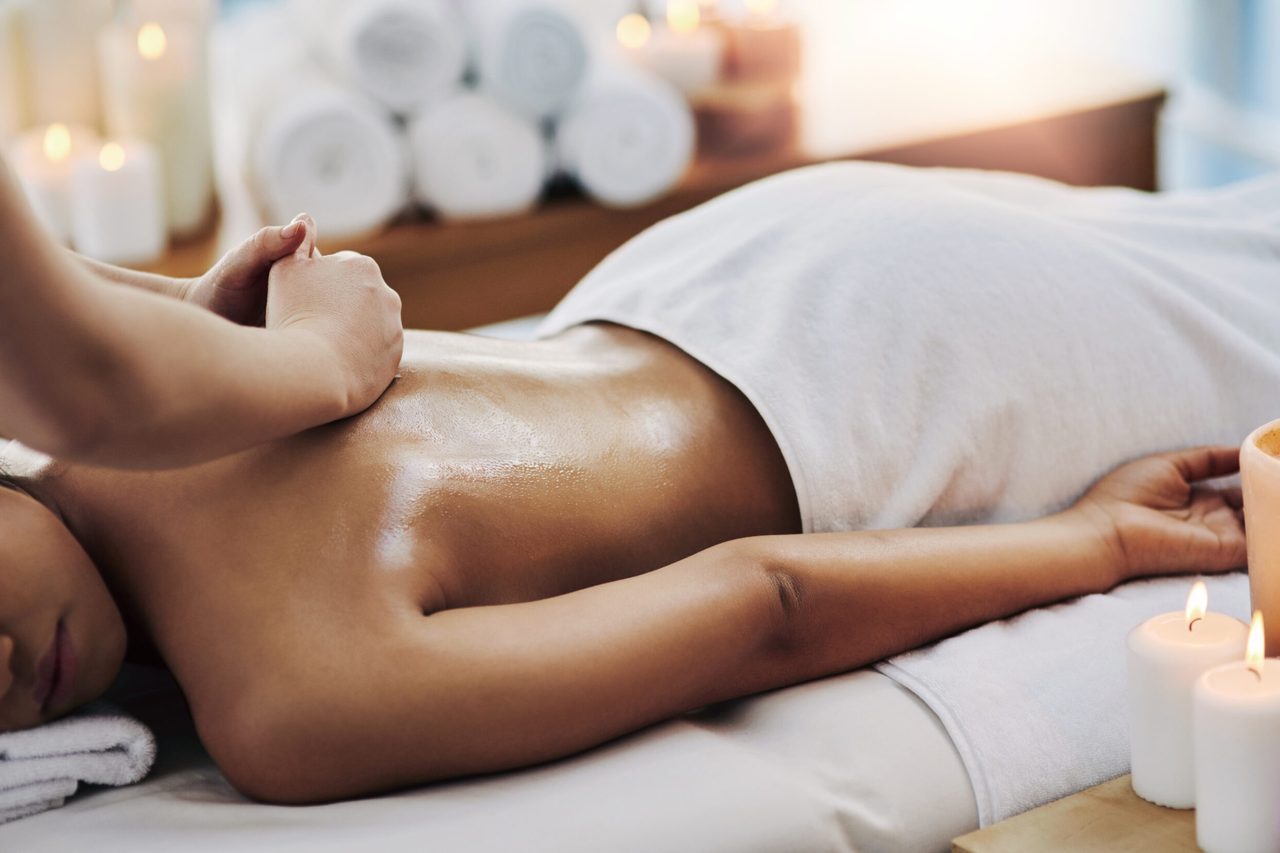 A back massage being given by candlelight on a treatment table.